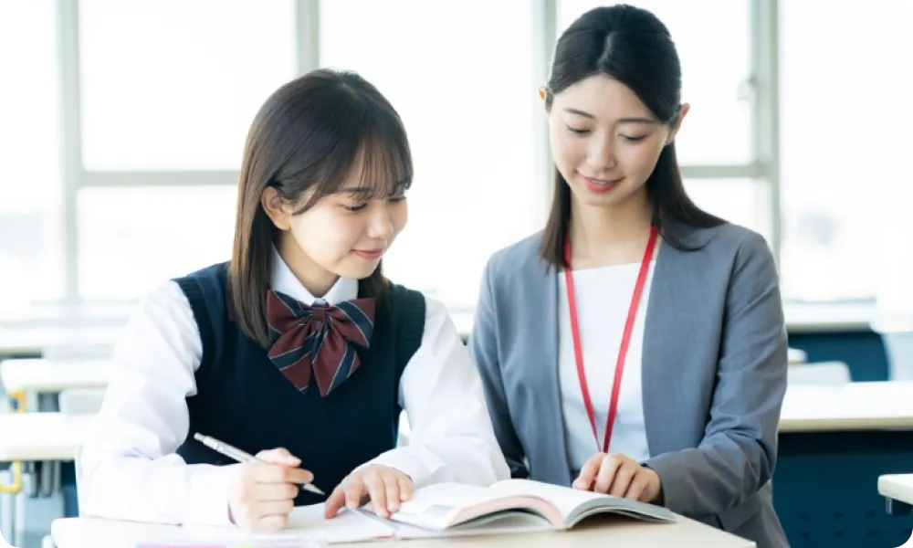 女子生徒に勉強を教える女性の画像